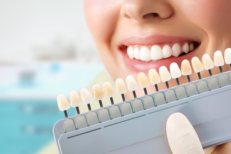 Mujer sonriendo y mano sosteniendo implantes dentales