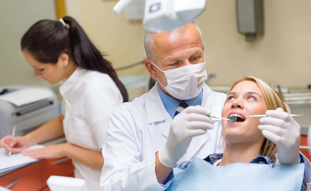 dentista revisando paciente y asistente atras periodoncia e implantes monterrey