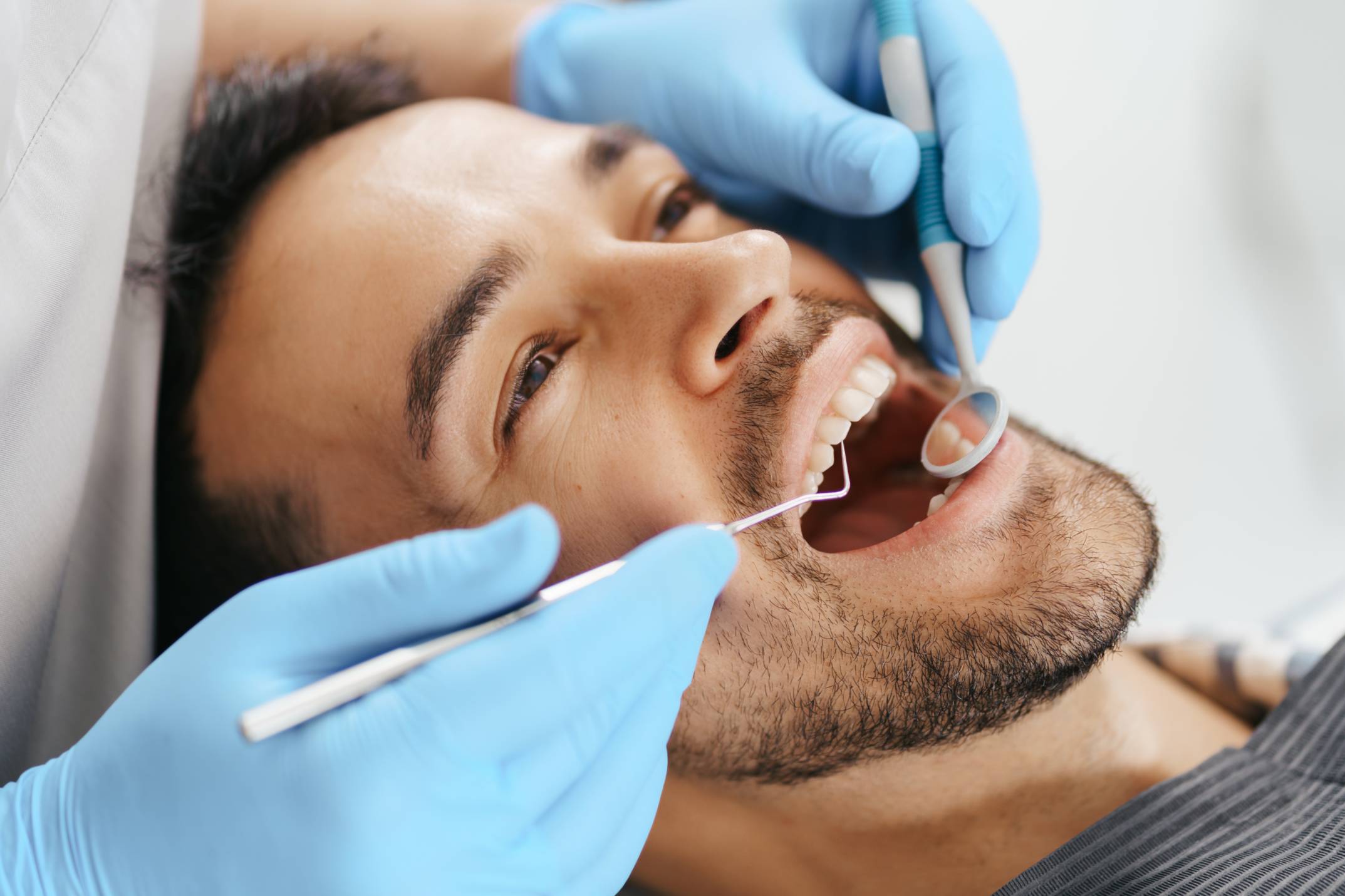 Hombre con la boca abierta mientras le hacen una limpieza dental