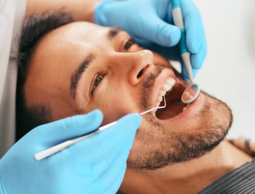 Joven con periodoncia sentado en la silla del dentista mientras el médico examina sus dientes